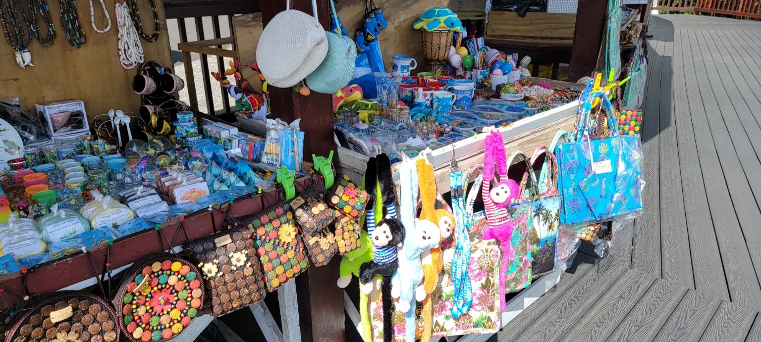 Colourful bags, hats, jewellery, mugs and soft toys fill a wooden craft and souvenir stall.